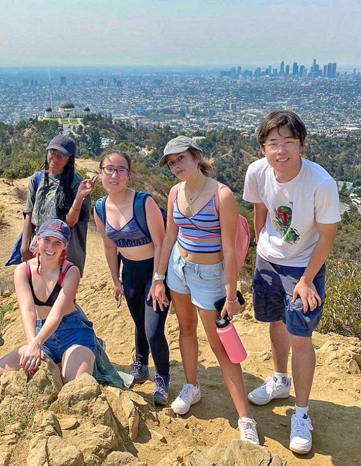 five students stand on top of a hill with downtown los angeles in the distance